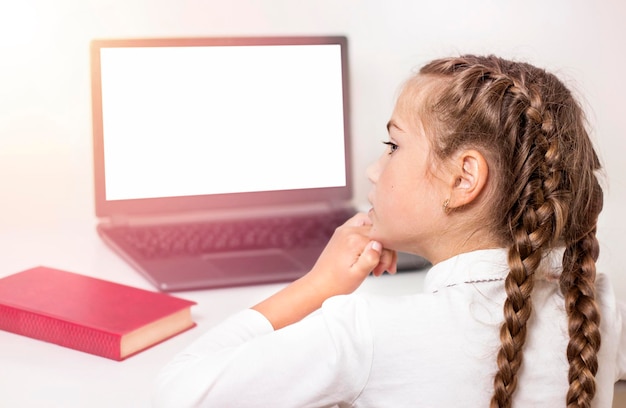 pensive schoolgirl sitting in front of a laptop close-up