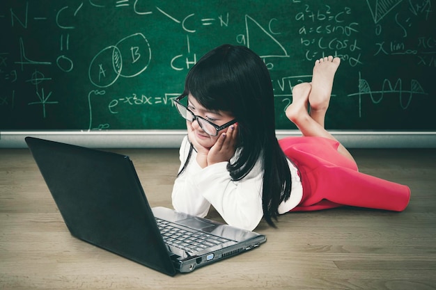 Pensive schoolgirl using a laptop in the class