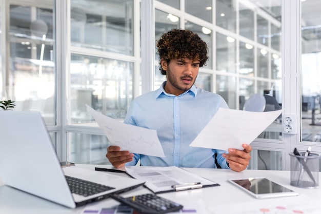pensive serious businessman reading financial report hispanic businessman holding document in hands