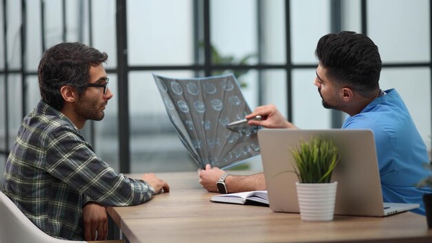 Pensive serious mature adult male physician consult shocked young man patient giving bad news