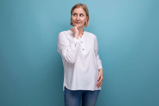 Pensive slender blondie middleaged woman in a white blouse