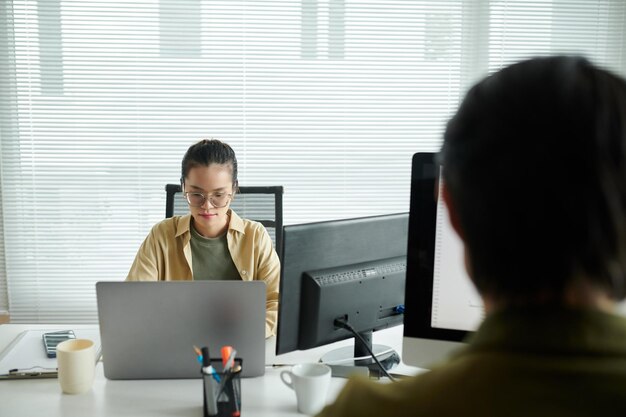 사무실 책상에서 노트북으로 일하는 사려 깊은 소프트웨어 개발자