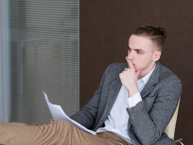 Pensive thoughtful business man at work contemplating over documents in office confident successful broker holding papers