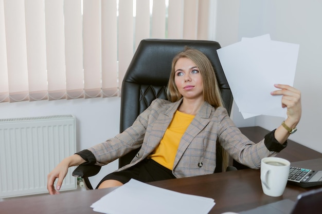 Pensive and tired female boss sitting at the table in her office