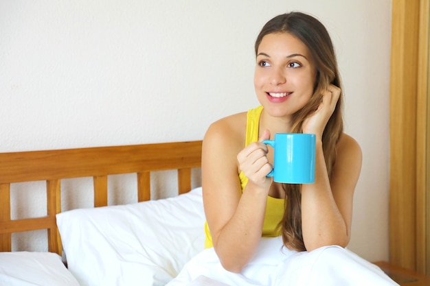 コーヒーやお茶を飲んで考えてベッドで物思いにふける女性