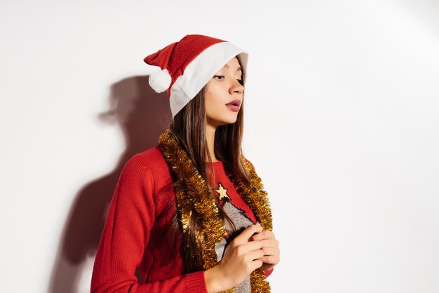 Pensive woman in a Christmas hat on a gray background