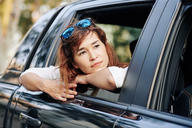 Pensive woman looking through car window