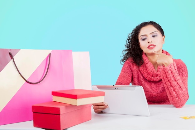 Pensive woman shopping online on studio