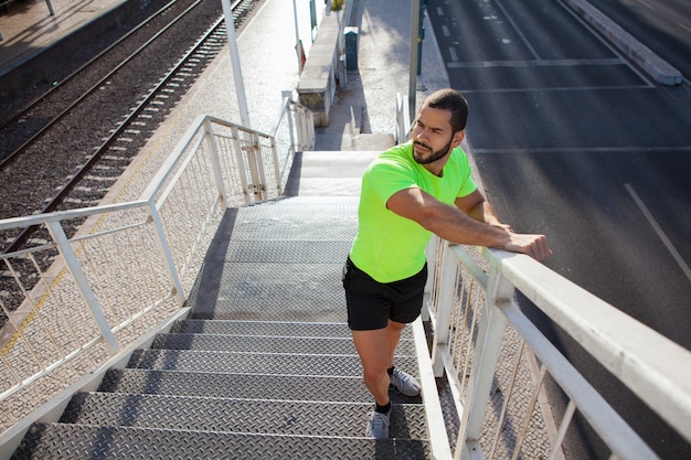 Pensive young athlete walking upstairs outdoors