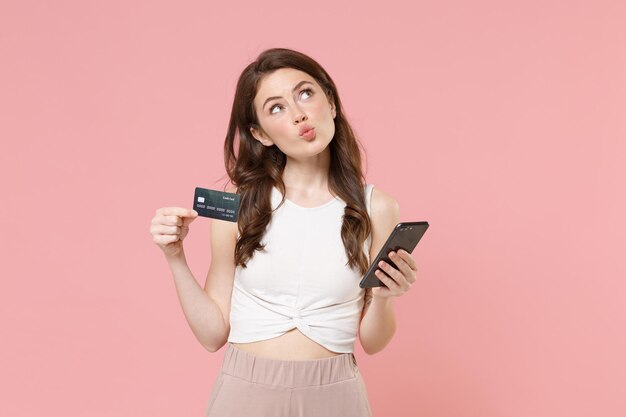 Pensive young brunette woman girl in light casual clothes posing isolated on pastel pink background