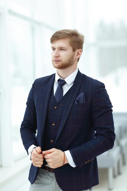 Pensive young businessman standing near the office window