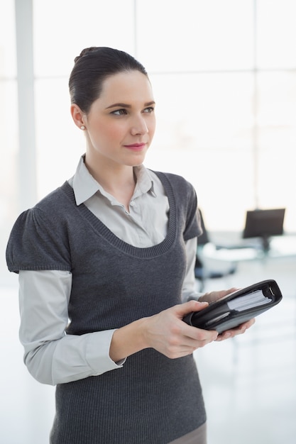 Pensive young businesswoman holding datebook