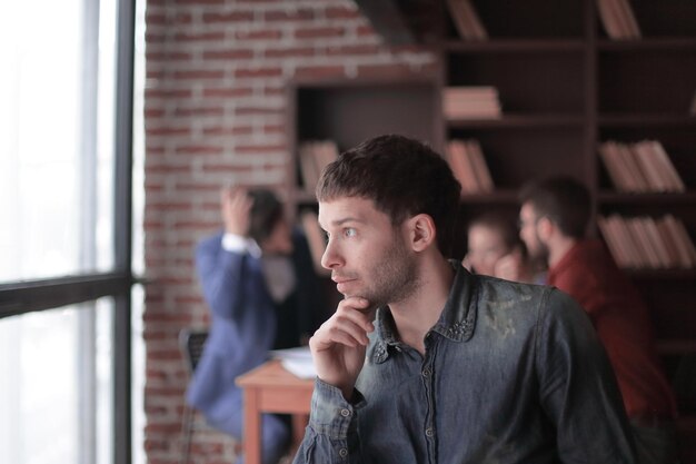 Фото Задумчивый молодой дизайнер смотрит в окно офиса