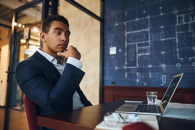 Pensive young engineer sitting at his computer