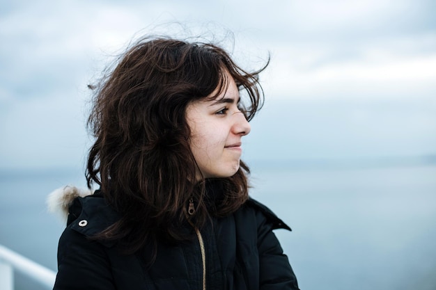 Pensive young girl looking to the sea from boat teenager girl\
at ferryboat cold grey sea