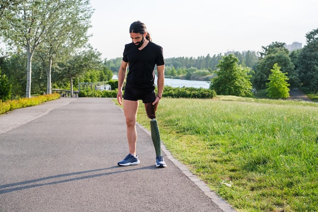 屋外でスポーツをしながら義足で物思いにふける若い男