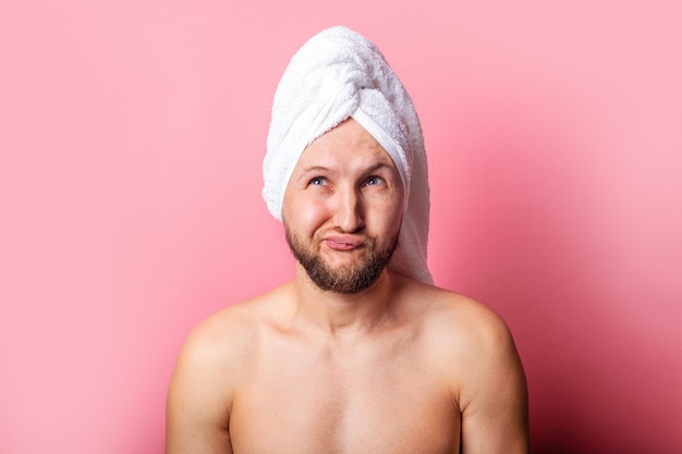 Pensive young man with a towel on his head on a pink background