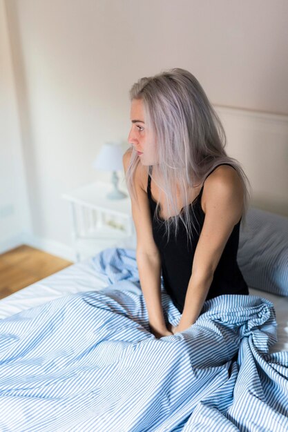 Pensive young woman in bed