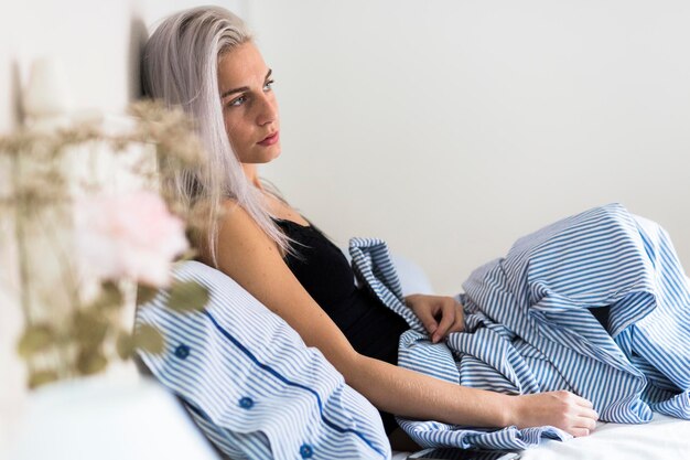 Pensive young woman in bed