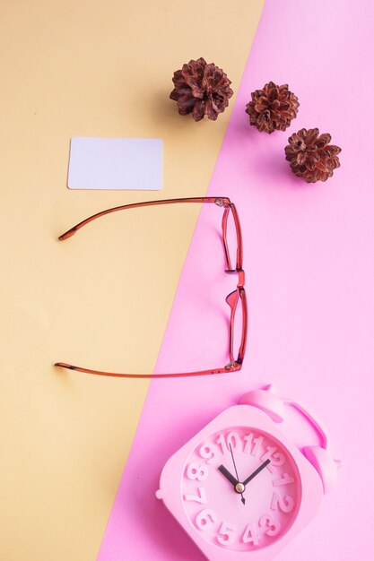 Pentagonal glasses in the photo in minimal summer style on a pastel pink and yellow background. Alarm Clock , Pine Tree Flowers , Business Cards