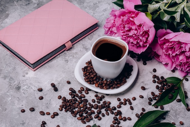 Peonies flowers on the table and a cup of coffee