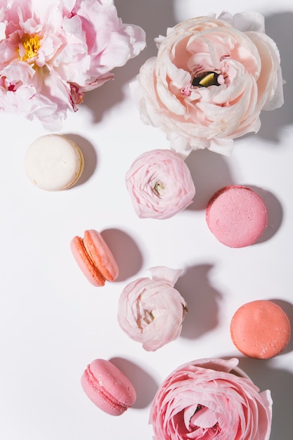 peonies flowers with macaroons on white background top view