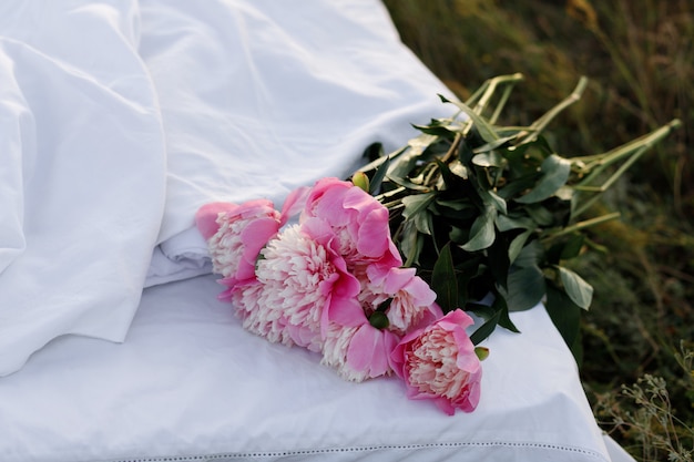 Peonies on white beds in summer in nature