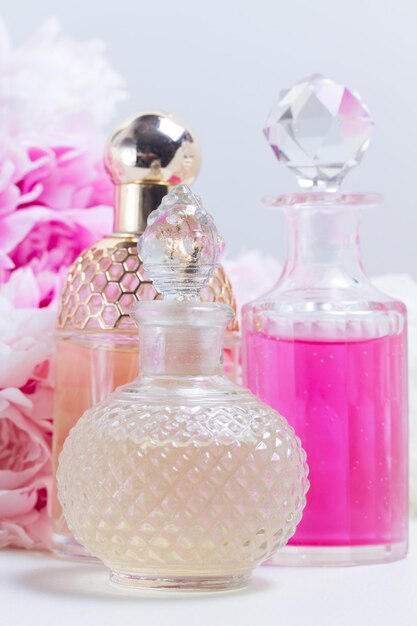 Peony essence oil and water in glass vials and fresh peony flowers close up