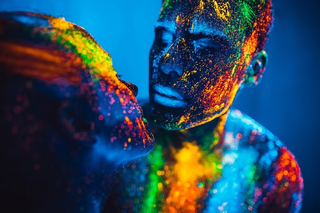 Le persone sono colorate in polvere fluorescente. una coppia di innamorati che balla in discoteca.