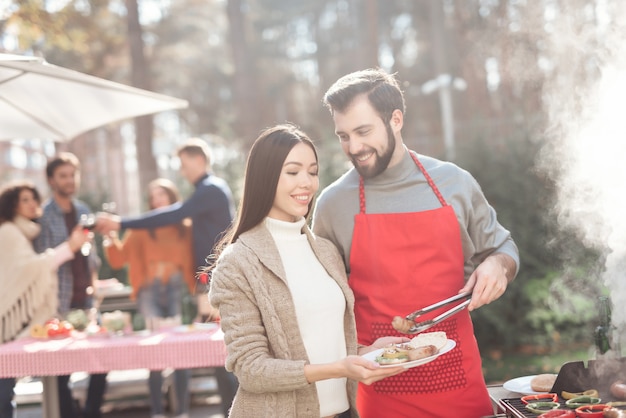 Le persone stanno cucinando cibo barbecue durante un picnic.