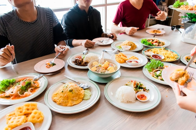 人々はたくさんの食べ物をテーブルに置いて食べ物を食べています。