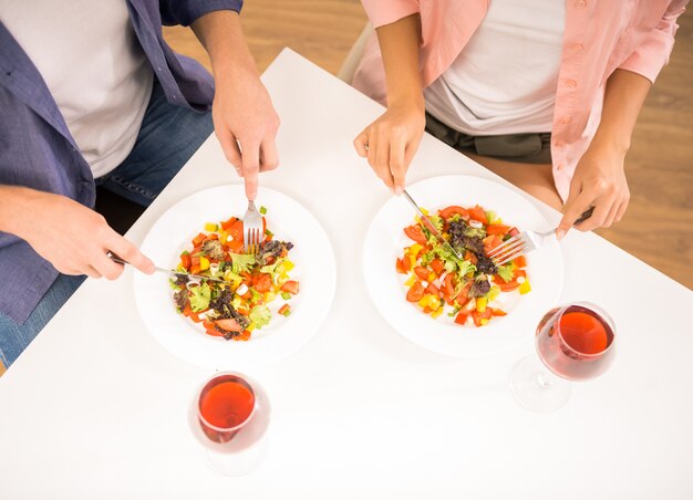 People are eating salad in kitchen.