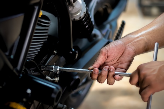 Люди ремонтируют мотоцикл Используйте гаечный ключ и отвертку для работы.