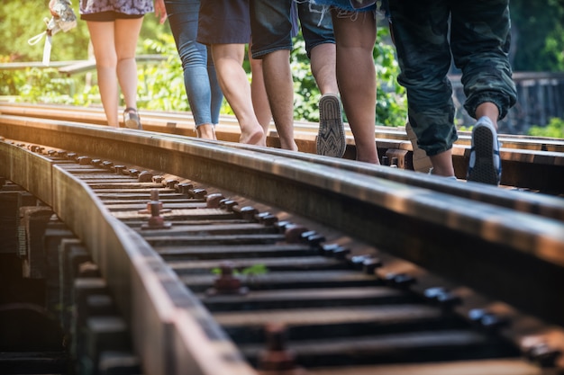 人々は、死の鉄道で暖かい日光の下で鉄道を歩いています。