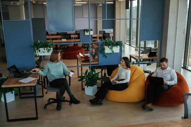 Фото Люди работают в офисе с бобовыми мешками и стульями.