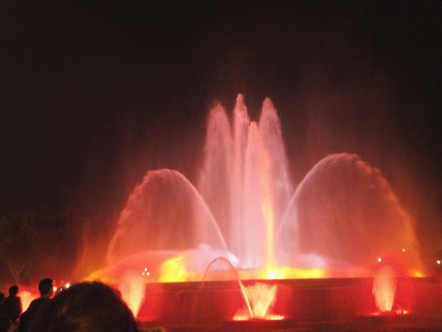 Фото Люди у фонтана против фейерверка ночью