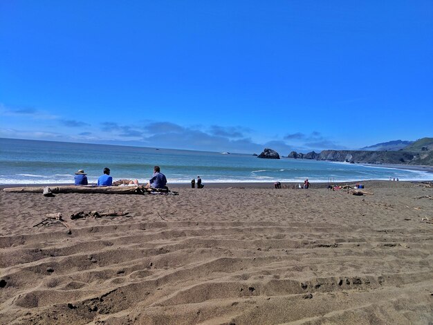 People at beach against blue sky