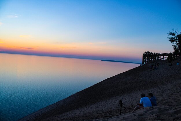 People on beach against sky during sunset