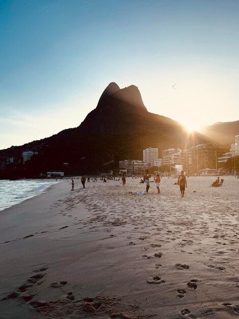 People at beach against sky during sunset