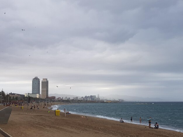 People on beach by buildings against sky