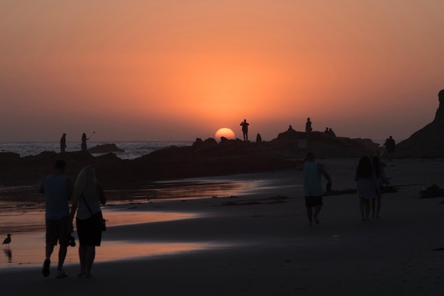 Foto persone sulla spiaggia durante il tramonto