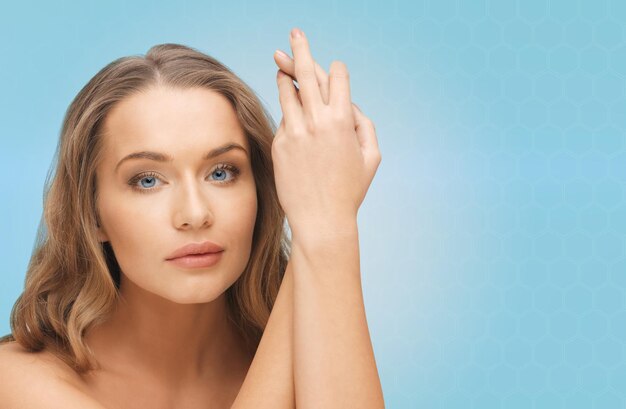 Photo people, beauty, body and skin care concept - beautiful woman face and hands over blue background