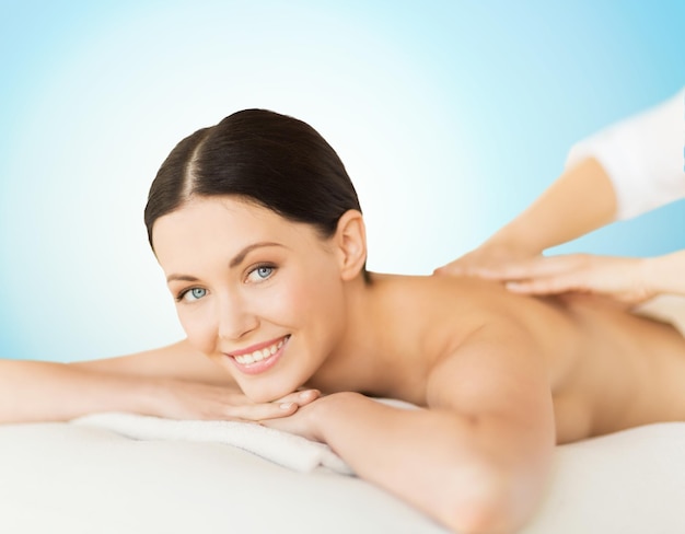 people, beauty, spa and body care concept - happy beautiful woman having back massage over blue background