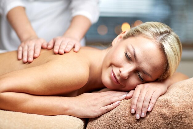 people, beauty, spa, healthy lifestyle and relaxation concept - close up of beautiful young woman lying with closed eyes and having hand massage in spa