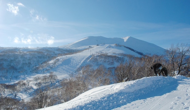 은 하늘을 배경으로 눈 인 산에서 구부리는 사람들