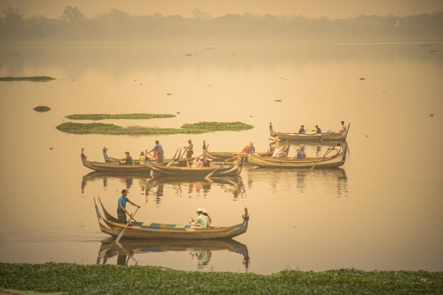 Photo people on boats in lake during sunset