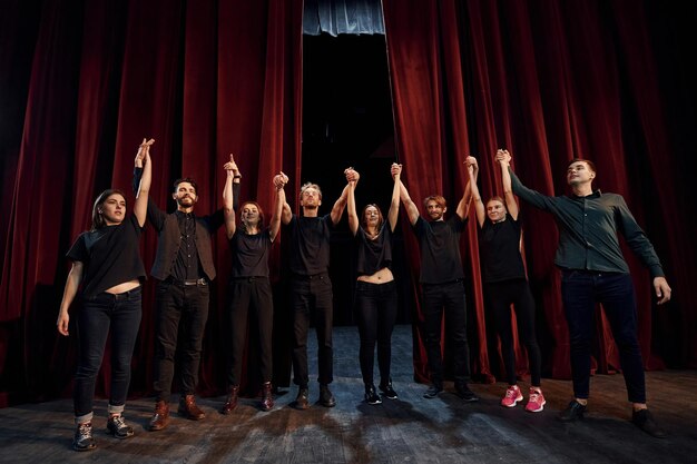 Photo people bowing to audience group of actors in dark colored clothes on rehearsal in the theater