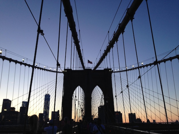 Foto persone sul ponte di brooklyn in città durante il tramonto