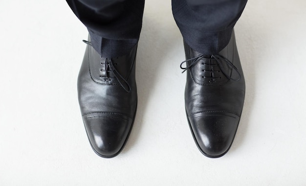 Концепция людей, бизнеса, моды и обуви - крупный план мужских ног в элегантных туфлях со шнурками или кружевными сапогами