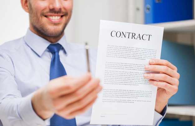 people, business and paperwork concept - close up of smiling businessman holding contract document